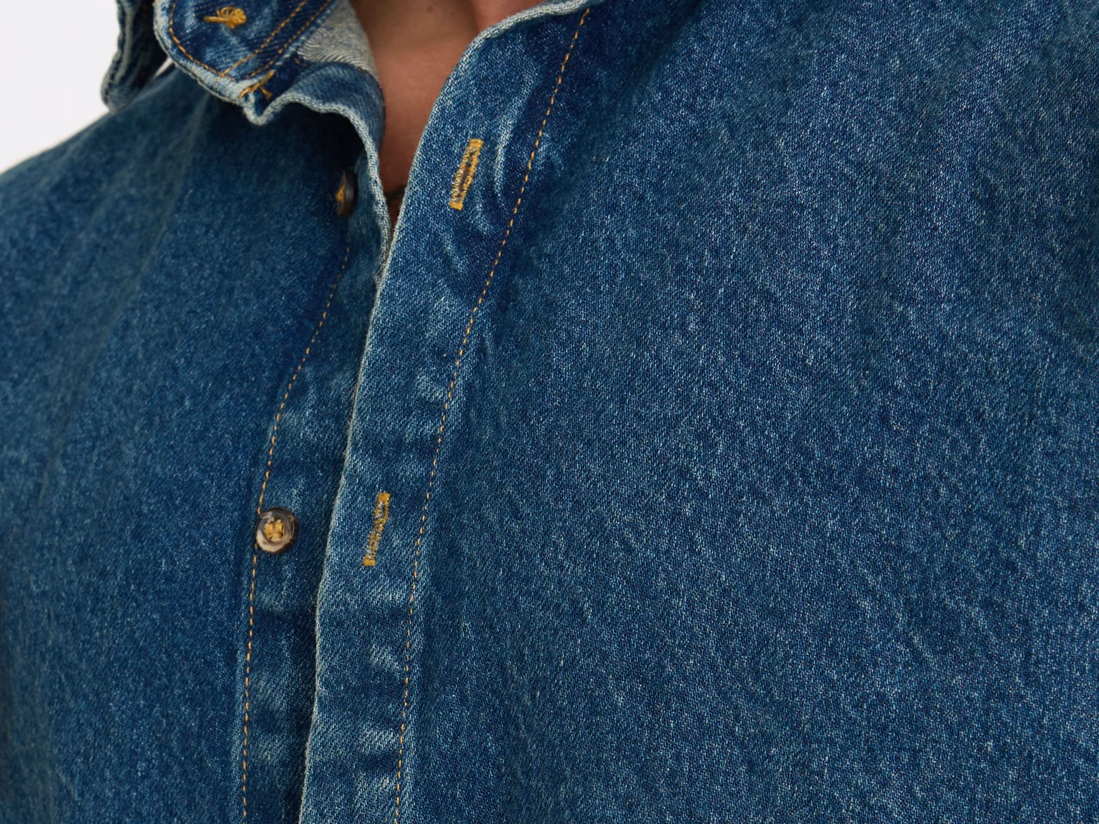 Collo e abbottonatura di una sovracamicia in denim blu medio