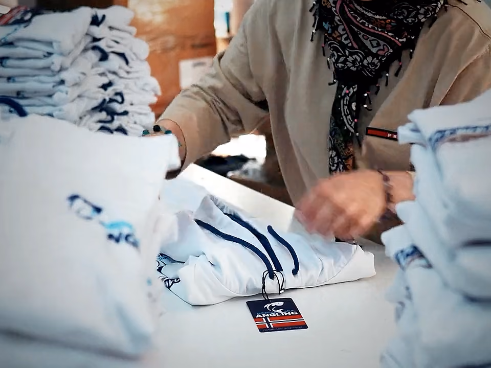 Addetta all'imballaggio che piega capi stampati con cartellino al tavolo di confezionamento