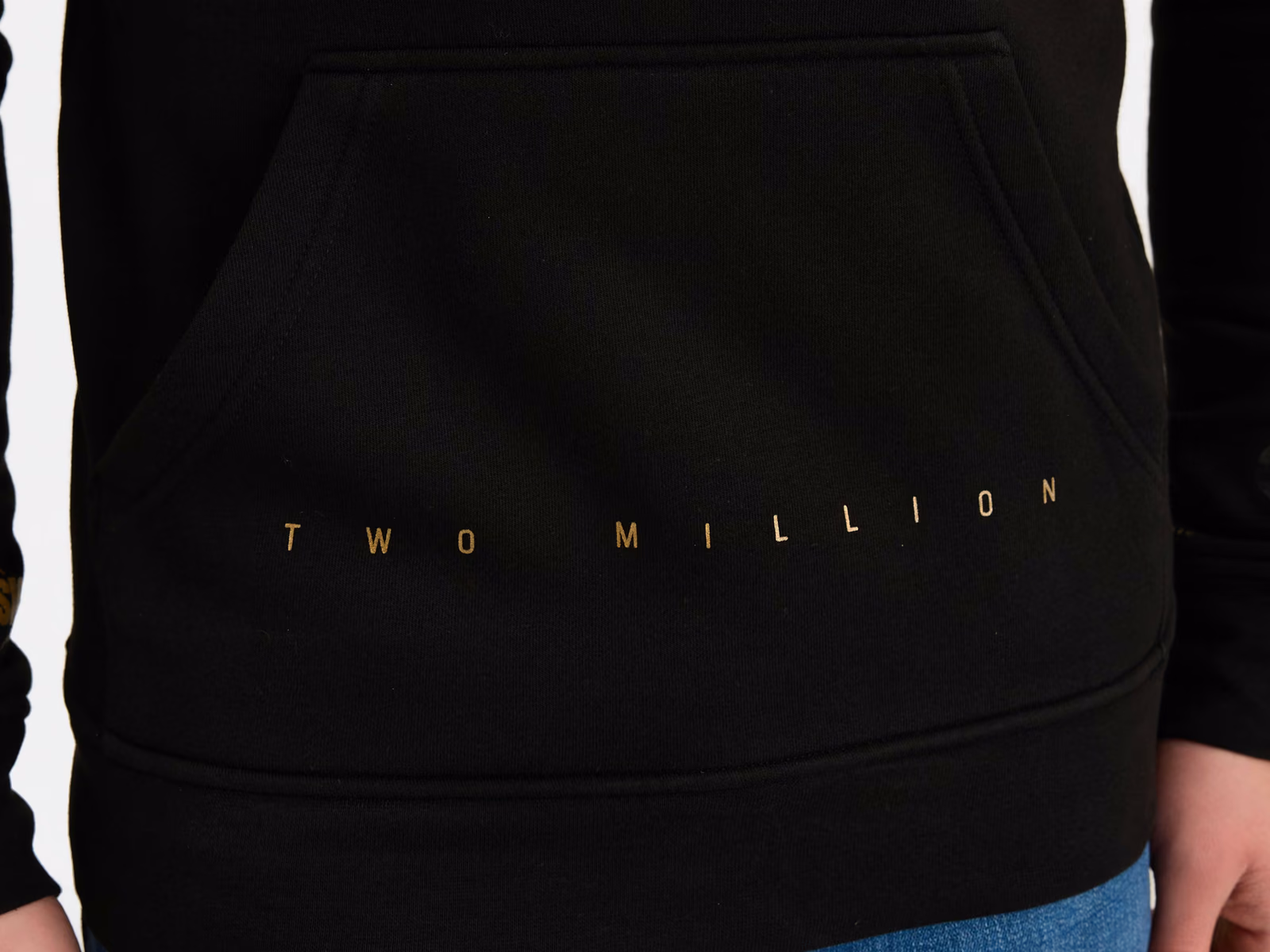 Kängurutasche und Saumbund eines schwarzen Hoodies mit feinem aufgedrucktem Text