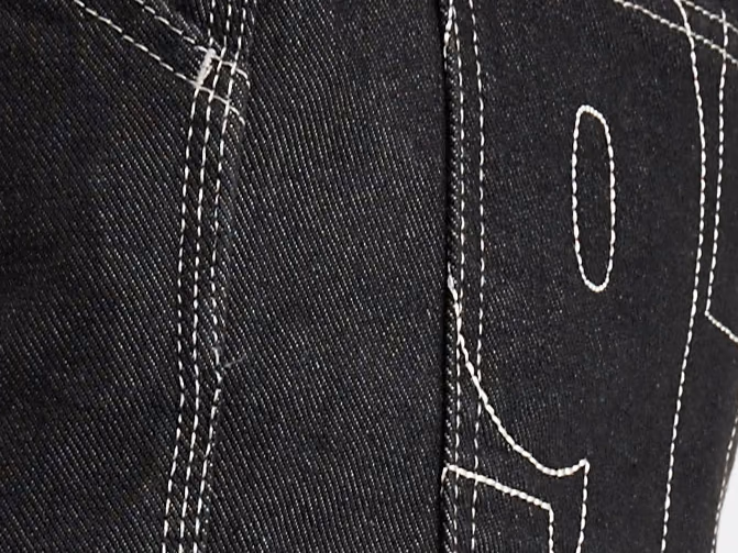 Nærbillede af dobbelte rækker hvid synlig stikning på sort denim