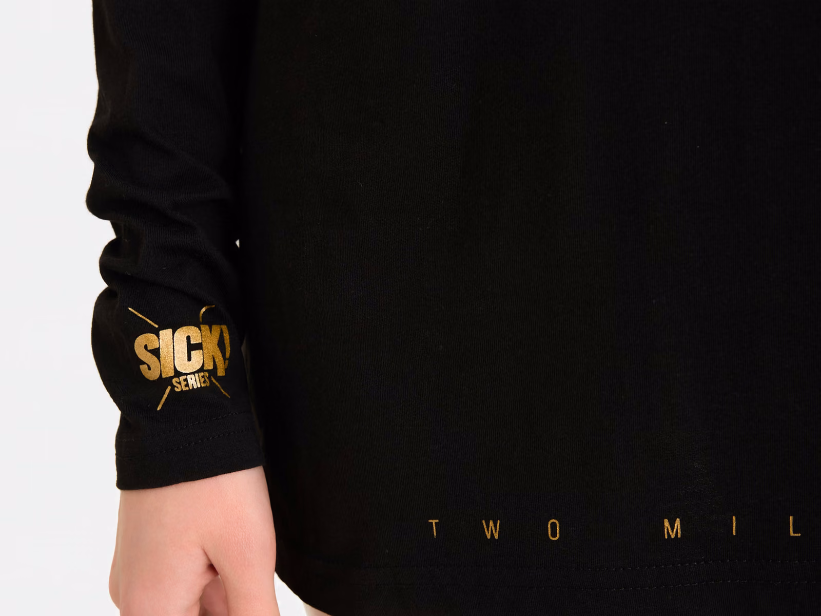 Rippbündchen mit kleinem Golddruck und Saum eines schwarzen Langarm-T-Shirts