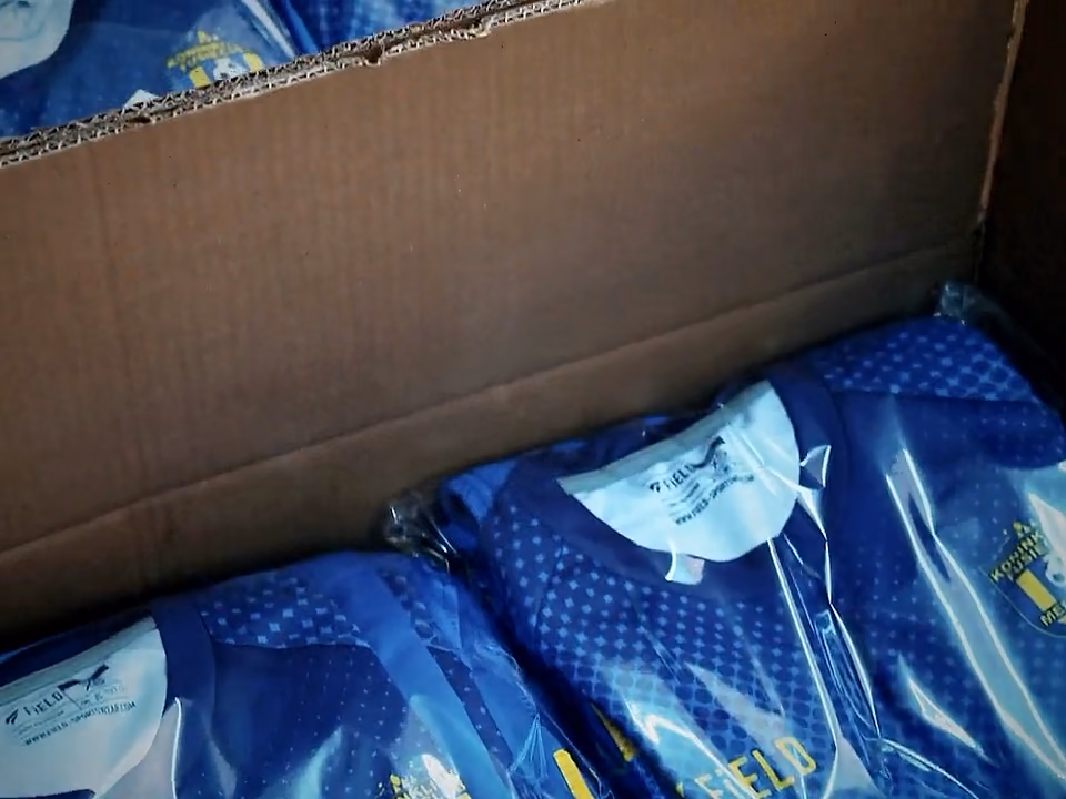 Offener Karton mit einzeln verpackten Fußballtrikots