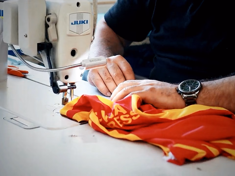 Operatrice alla macchina da cucire che assembla una maglia da gioco stampata