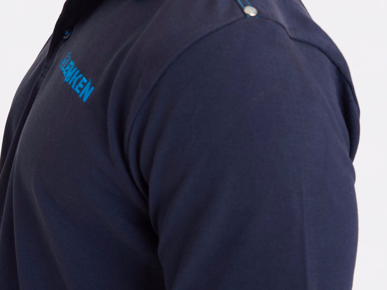 Cucitura della spalla e manica di una polo blu navy con un logo stampato sul petto