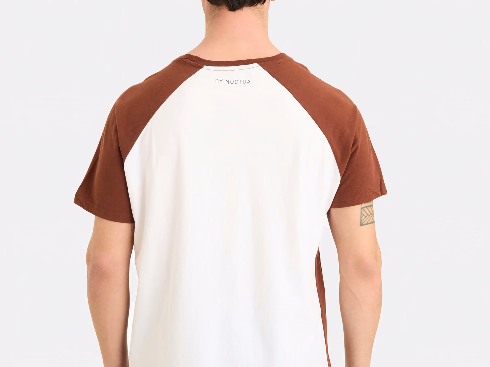 Vista posteriore di una t-shirt con maniche raglan marroni unite a un corpo bianco sporco