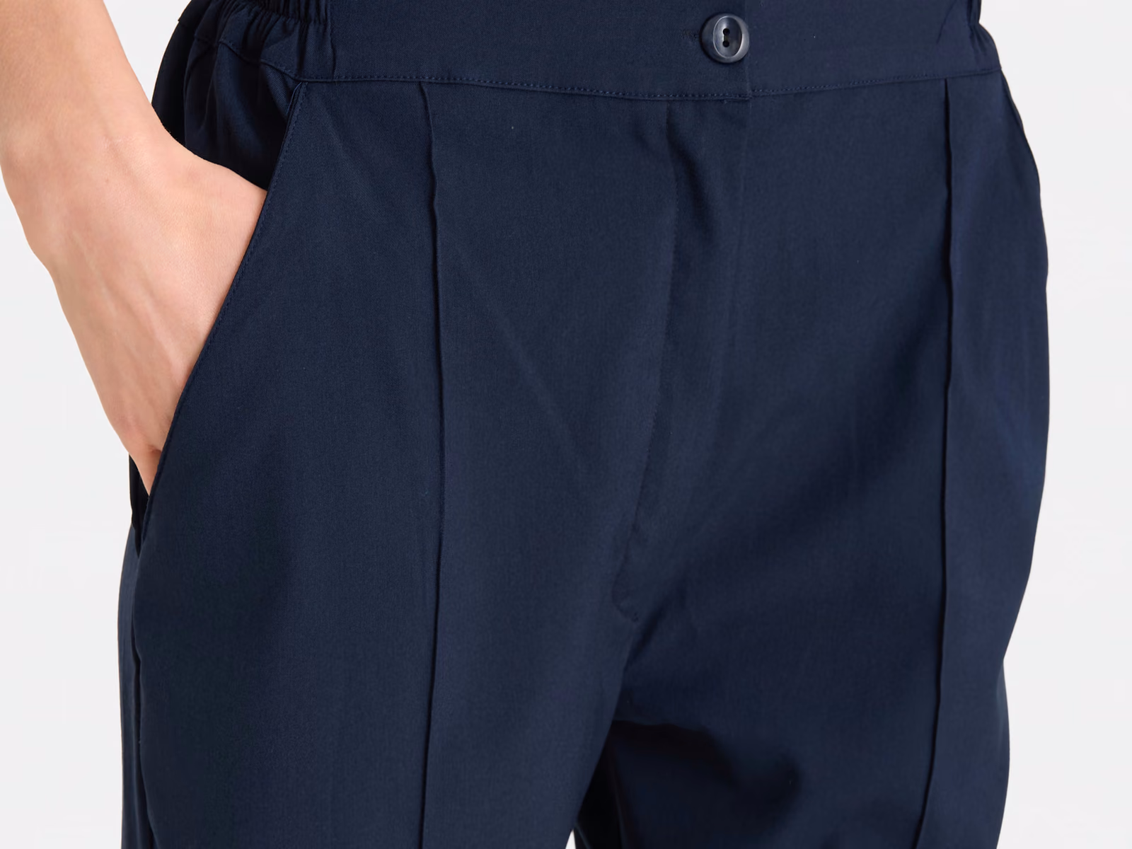 Bund mit Knopfverschluss und eingebügelter Bügelfalte vorn an einer marineblauen Uniformhose