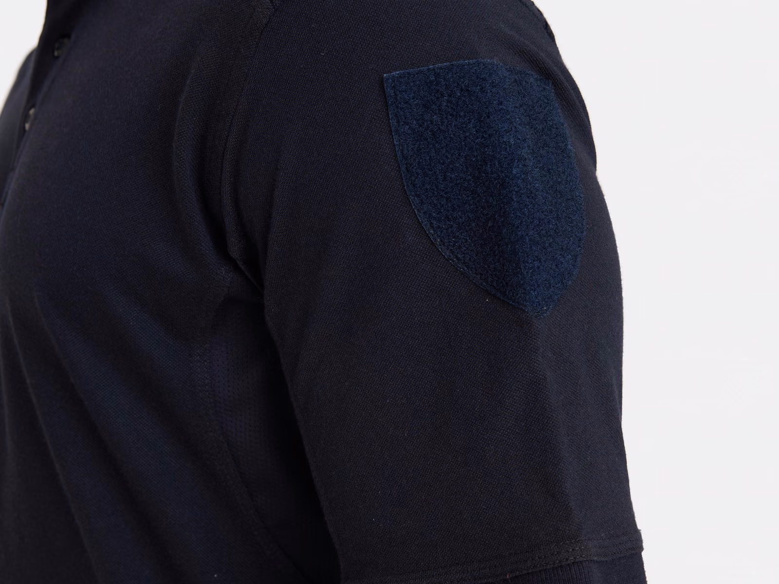 Ærme på en marineblå uniformsskjorte med burrebåndspanel til et aftageligt emblem